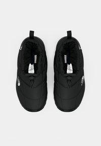 Juoda pora izoluotų šlepečių su kilpomis ir The North Face logotipais ant balto fono.