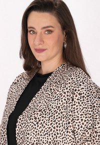 Leopárdmintás sál puha, könnyű anyagból. Laza fazonú, fekete részletekkel, egy fekete felső alatt kombinálva.