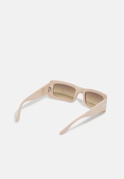 Ochelari de soare dreptunghiulari din plastic mat de culoare bej deschis, având lentile maro cu gradient și brațe aerodinamice cu un detaliu subtil al logo-ului.