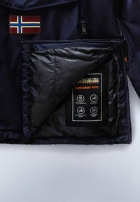 Dunkelblaue Jacke geöffnet, um ein Innenfutter mit Eigenschaften zu zeigen: wasserabweisend, winddicht, getapte Nähte und atmungsaktiver Stoff.