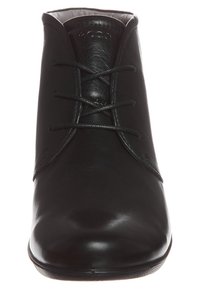 Botas de tobillo de cuero negro con un acabado suave, puntera redonda y diseño de cordones. Cuentan con un tacón bajo y un detalle de costura minimalista.