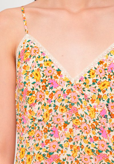 Camiseta floral en crema con flores en tonos rosa brillante, amarillo y naranja. Delicada puntilla en el escote en V y tirantes ajustables.