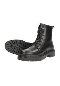 Zwarte leren enkelboots hebben een ronde neus, een vetersluiting aan de voorkant en een dikke rubberen zool met een gestructureerd grippatroon.