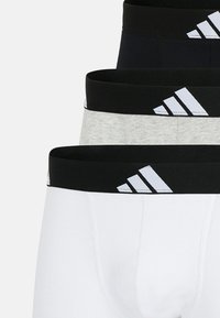 Tre par herrboxershorts i svart, grått och vitt, varje med en svart elastisk midja som har en vit logotyp och randdetalj.
