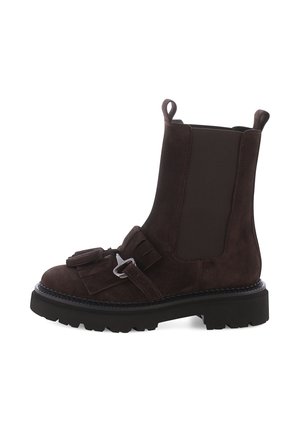 Botte de cheville en suede marron foncé avec semelle noire épaisse, panneaux latéraux élastiques, détail à pompon et boucle en argent à l'avant.