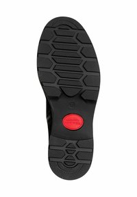 Black shoe sole featuring a hexagonal tread pattern, textured surface, and a prominent red circular logo marked "Tamaris Comfort."