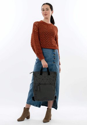 Borsa a tracolla grigia con motivo geometrico e due manici neri, abbinata a un maglione lavorato a maglia testurizzato color ruggine e una gonna di jeans blu.