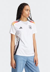 Adidas dres njemačke reprezentacije u bijeloj boji, s crnim i crvenim akcentima, s okruglim izrezom i izvezenim logotipom. Izrađen od prozračnog materijala.