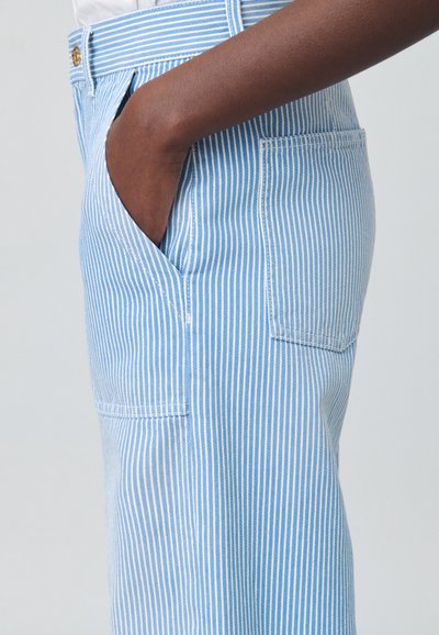 Pantalon rayé bleu et blanc à coupe droite, avec poches latérales et ceinture. Fabriqué en tissu léger, à texture lisse.