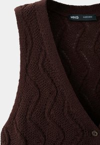 Gilet sans manches tricoté marron foncé avec motif ondulé et bouton, étiqueté MNG, taille EU USA S TWEK CH.