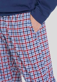 Pantaloni da pigiama a quadri in rosso, blu e bianco, realizzati in tessuto leggero con cintura elastica e tasche laterali.
