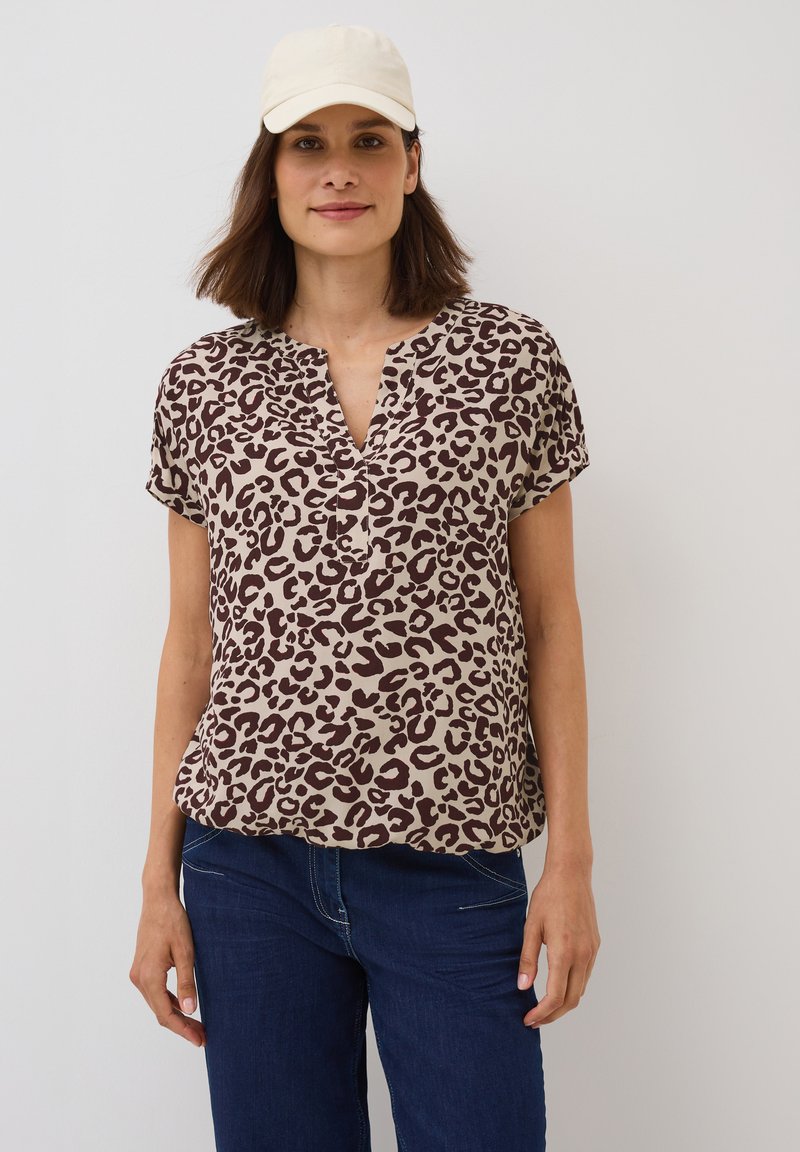Top à imprimé léopard en beige et marron, à manches courtes, décolleté en V, en tissu léger, assorti à un pantalon en denim noir à coupe décontractée.