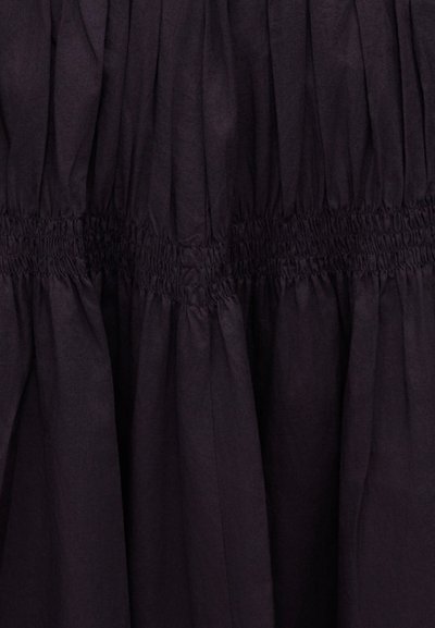 Tissu noir avec smocks élastiqués froncés créant des bandes horizontales texturées et des plis verticaux.