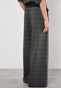 Bredde bukser i et sort og gråt ternet mønster. Lavet af et tekstureret stof med en glat waistband og en afslappet pasform.
