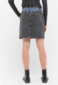 Denimrock in Dunkelgrau, mit einem hellblauen Bund, zwei Gesäßtaschen und geradem Schnitt. Saum mit Fransen.