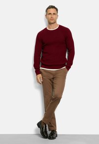 Maroon knit sweater with white crew neck collar, paired with tan chinos and black loafers, featuring a relaxed fit and ribbed cuffs.