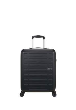 Valigia rigida nera con scanalature orizzontali, quattro ruote e manico telescopico esteso, con il marchio American Tourister sul lato frontale.