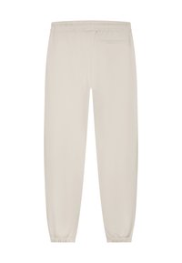 Lichtbeige, elastische broek met enkelschoenen en een enkele achterzak. Glad stof met een eenvoudige uitstraling. Geen zichtbare patronen of accenten.