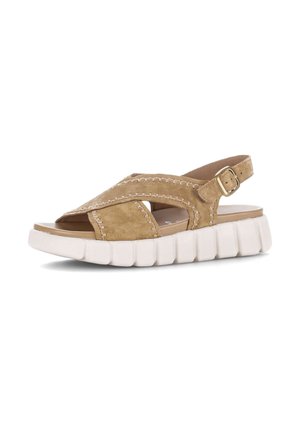 Tan suède sandaal met witte chunky zool, gekruiste bandjes, open teen en verstelbare gesp sluiting op een witte achtergrond.