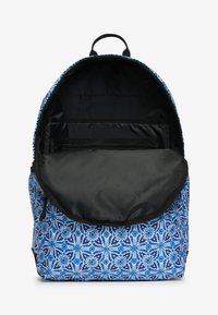 Mochila azul con un diseño de flores, que presenta un interior negro, bolsillos con cremallera y una asa superior para llevar.