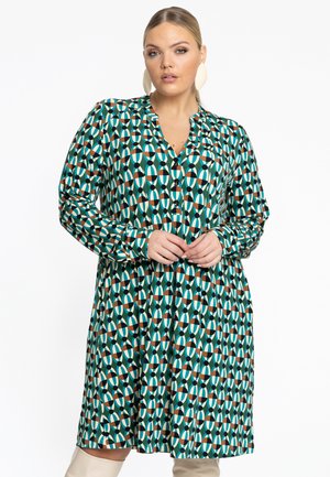 Robe verte avec un motif géométrique en teal, orange, crème et noir. Dispose d'un décolleté en V, d'une fermeture par bouton et de manches longues.