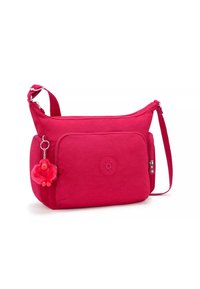 Rosa nylon axelväska med en framficka med dragkedja, en rund logotyp och en fluffig apnyckelring som är fäst. Justerbar rem för bekväm bärning.