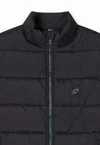 Schwarze Steppjacke mit hohem Kragen, horizontalem Quilt-Design und einem Reißverschluss auf der Vorderseite. Verfügt über ein kleines Logo-Patch auf der linken Seite.