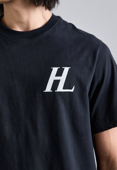 Mustast puuvilla T-särk, mille vasakul rinnal on valge "HL" logo. Kangas näeb välja sile ja klassikalise ümarate kaelustega.