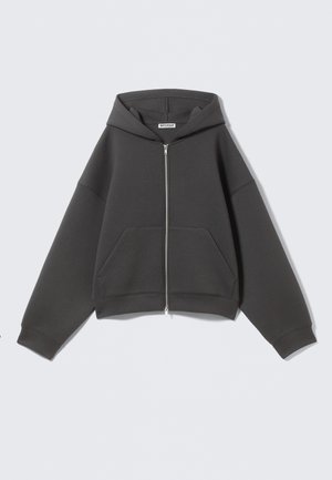 Pelēks zip-up kapuce, izgatavota no mīksta auduma ar brīvu piegriezumu, lielām priekšējām kabatām un kapuci ar aukliņu. Vienkāršs dizains, bez rakstiem.