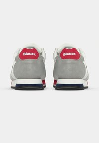 Paire de baskets grises et blanches avec languettes rouges au talon présentant le logo blanc Blauer, vues de dos sur un fond simple.
