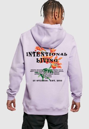 Felpa di colore lavanda con una grande grafica sulla schiena, che presenta accenti floreali e testo audace che recita "VITA INTENZIONALE" e frasi aggiuntive.