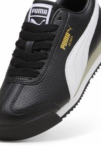 Musthave musta nahast toss, millel on valge triip, tekstureeritud pind, mustad paelad ja kuldne Puma bränding. Omab kummist talda ja pehmendatud kaela.