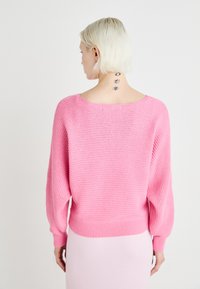 Roosa kudum koos lõtvade varrukatega ja äärega. Omab laia kaelust ja peent horisontaalset tekstuuri.