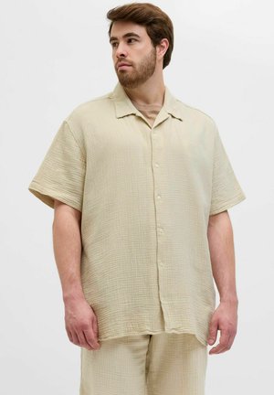 Kurzärmliges Hemd aus leicht beige strukturiertem Stoff, mit durchgehender Knopfleiste und einem lockeren Schnitt, kombiniert mit passenden Hosen.
