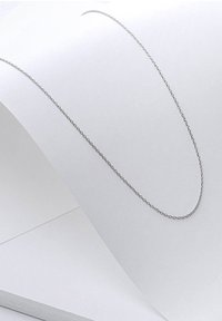 Zilveren ketting neergelegd op wit papier. De ketting heeft ronde schakels en een delicate, dunne vormgeving.