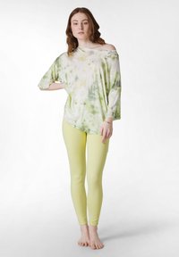 Överdimensionerad ljusgrön och vit tie-dye topp med batwingärmar, tillsammans med figursydda ljusgula leggings.