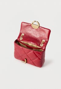 Κόκκινο δερμάτινο τσαντάκι χιαστί με επένδυση και λεπτομέρειες σε χρυσό, ανοιχτό για να φαίνεται η μπεζ εσωτερική φόδρα και η εσωτερική τσέπη.