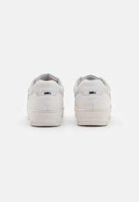 Vita lädersneakers med texturerad yta, stoppad krage, kontrasterande marinblå och ljusblå detaljer bak, gummisula med mönster.
