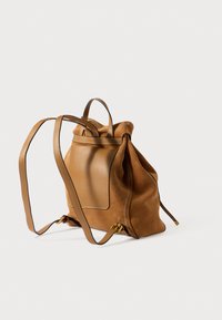 Hnědý semišový batoh s koženými detaily, uzavíráním na stahovací šňůrku, nastavitelnými popruhy a přední kapsou. Hladká textura s jemným leskem.