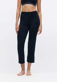 Pantalons de sport courts bleu marine avec une taille ajustée, texture lisse et détails subtils au niveau de l'ourlet, portés pieds nus.
