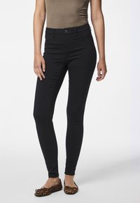 Sorte, tettsittende jeans med middels høy liv, glatt tekstur og fem lommers design. Brukt med leopardmønstrede leiligheter for kontrast.