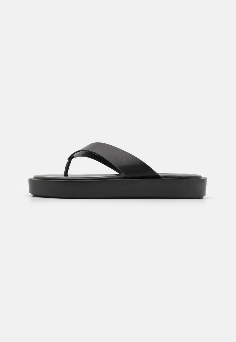 Sorte flip-flopsandaler med en glatt overdel og en teksturert plattformsåle. Minimalistisk design med en lavprofil silhuett.