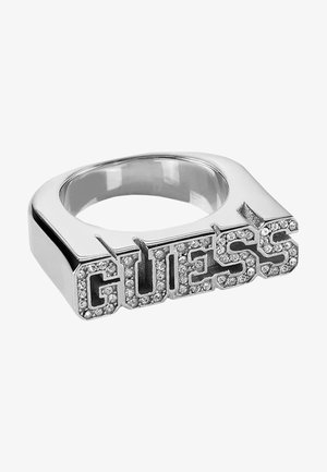 Bague ton argent avec une bande carrée portant le mot « GUESS » en lettres majuscules ornées de cristaux sur le dessus.