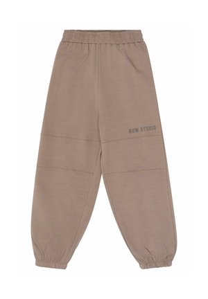 Pantalon de jogging taupe avec taille élastique et poignets froncés, avec le texte « NOW STUDIO » sur la partie supérieure de la jambe gauche, présenté sur fond blanc.