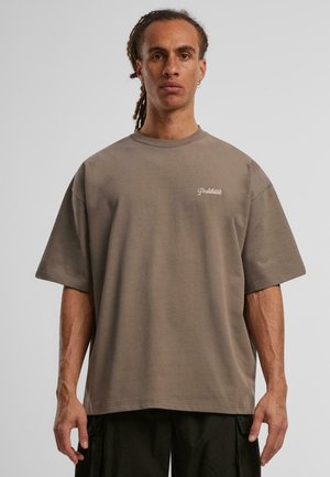 Oversized brown t-shirt in soft cotton, featuring a crew neck and short sleeves. Small "Prohibited" logo in light embroidery on chest.