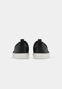 Zwarte, gladde leren sneakers met een witte rubberen zool, voorzien van een achterste trekhaak en een minimalistisch ontwerp.