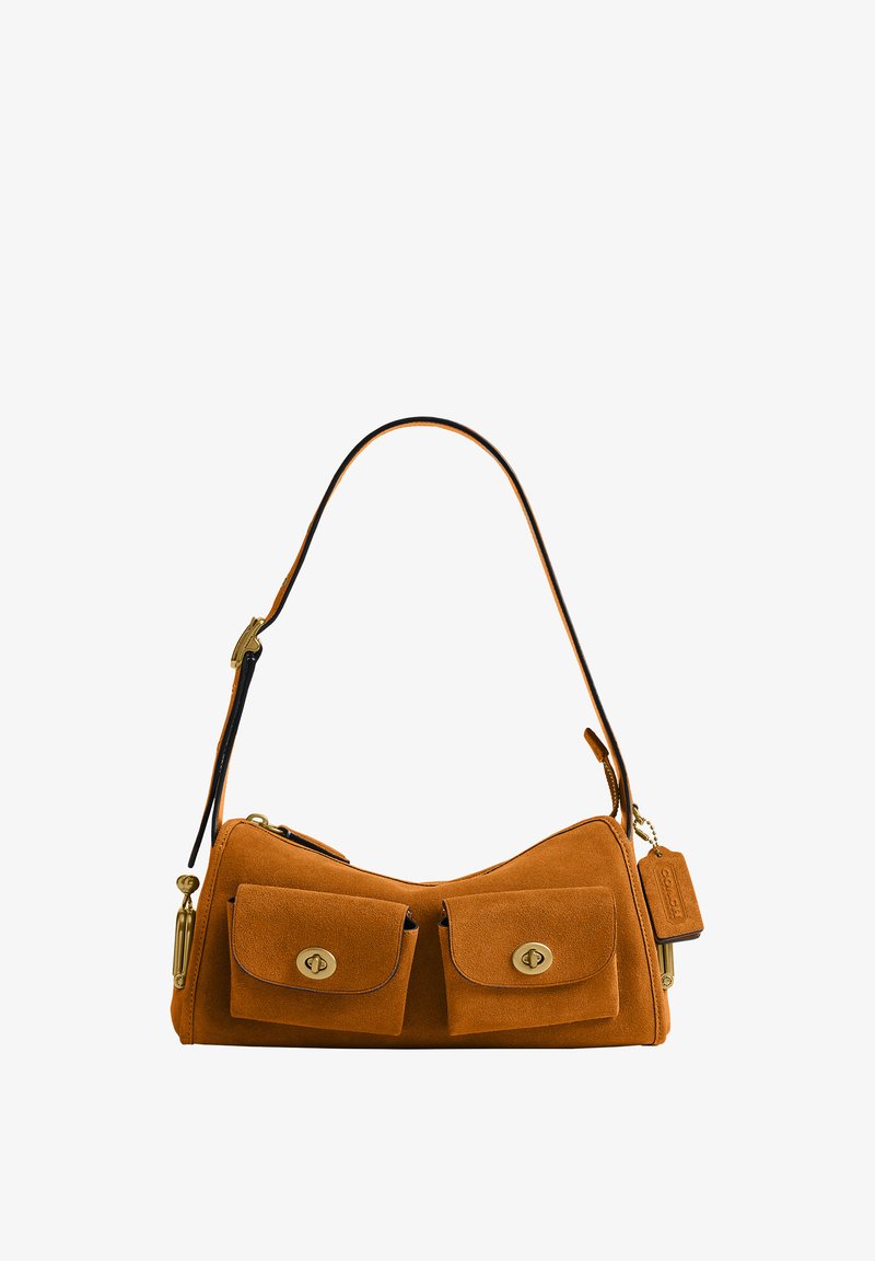 Sac à main en daim marron avec deux poches avant, fermoirs dorés, une bandoulière unique et une étiquette en cuir suspendue sur fond blanc.