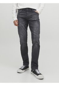 Mörkgrå denimjeans med slim fit, lätt blekning, femfickorsdesign och standardknapp- och dragkedjestängning, kombinerat med svarta sneakers.