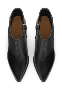 Botas de tobillo de cuero negro con punta afilada, cierre de cremallera lateral y textura suave. Costuras detalladas y diseño minimalista.