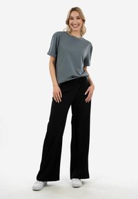 Gray short-sleeve shirt, black wide-leg pants, and white shoes. Smooth texture, relaxed fit, and clean lines throughout the outfit.